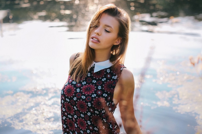 Woman with auburn hair in a floral dress by the water