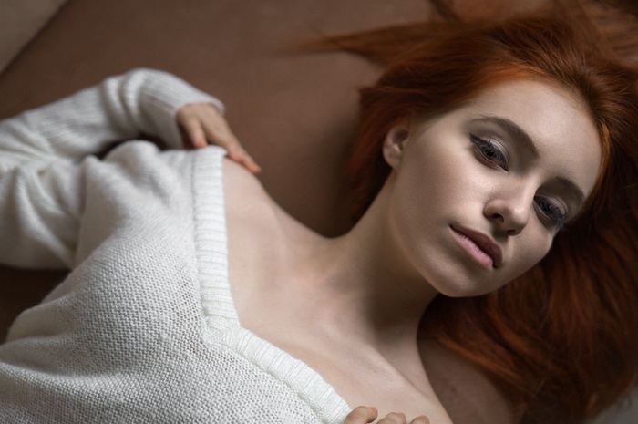 Redhead woman in white sweater lying down