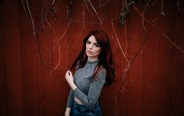 Redhead woman in striped shirt against a wooden wall