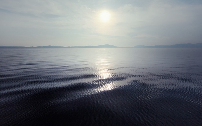 Sunlight reflecting on the sea with distant mountains