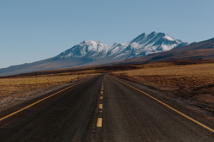 Road leading to snow-capped mountains under a clear sky
