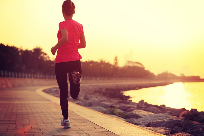 Woman running by the sea at sunset