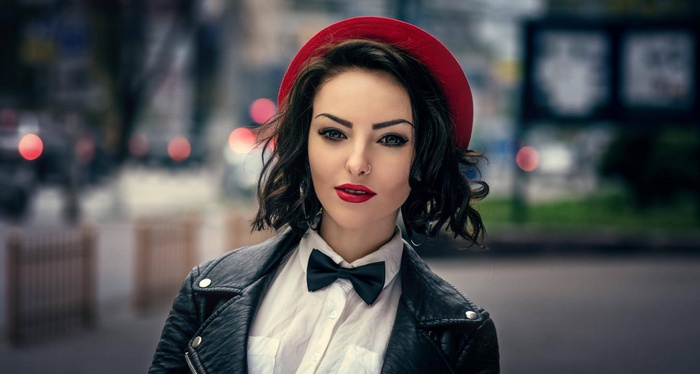 Woman in red hat and leather jacket with bow tie