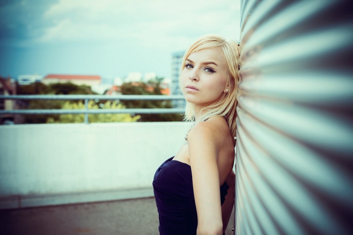 Blonde woman leaning against a corrugated metal structure