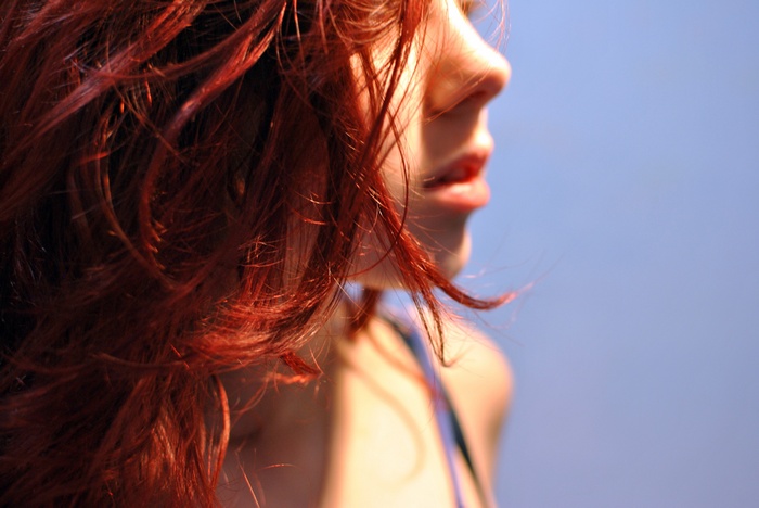 Redhead woman with long hair against blue background