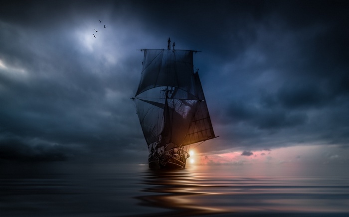 Sailing ship on the sea at sunset with storm clouds