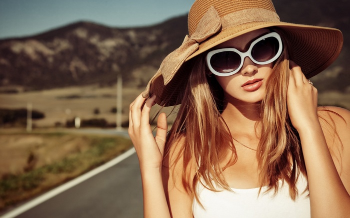 Woman in sun hat and sunglasses on a road