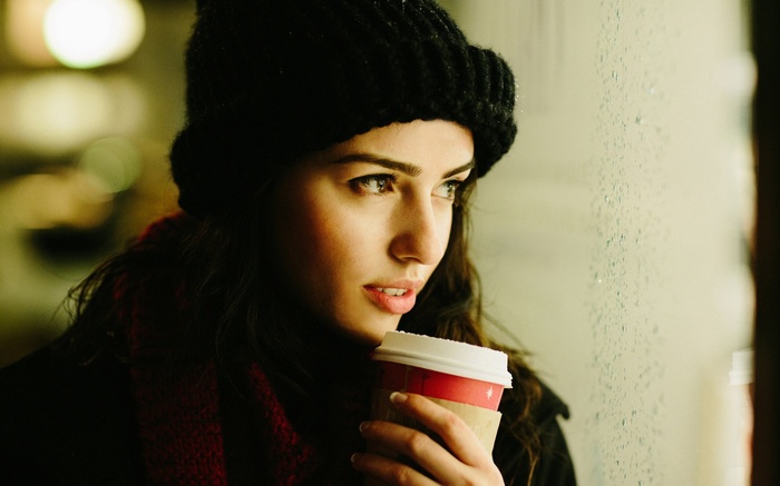 Woman in black hat holding a coffee cup