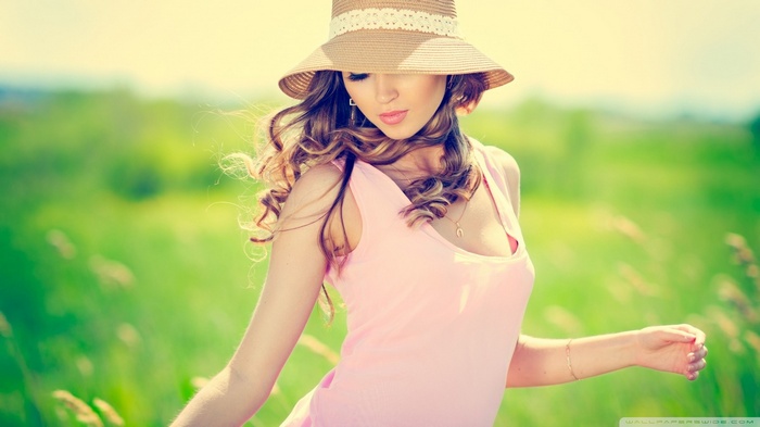 Woman in a hat and pink top in a field