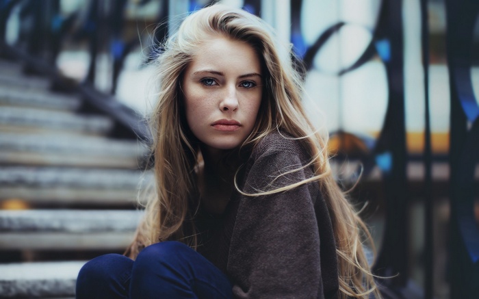Camille Rochette with blonde hair sitting on stairs