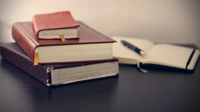 Stack of books and open notebook with pen