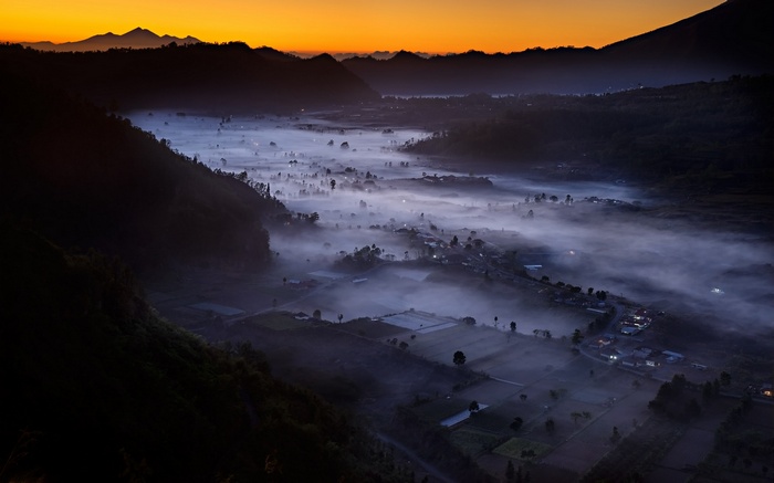 Misty valley with mountains at sunrise