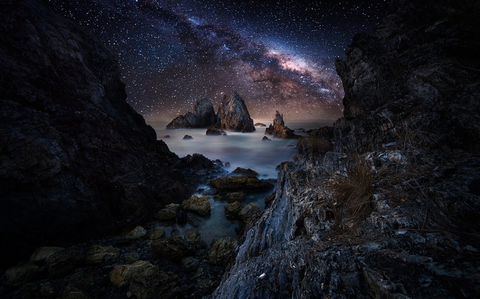 Milky Way over rocky coast with sea