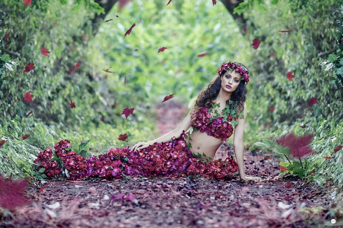 Woman in flower dress in forest with falling leaves