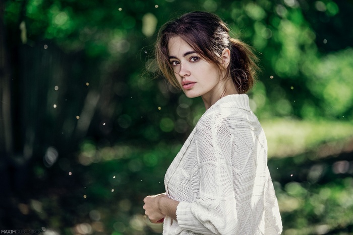 Woman with auburn hair in a white cardigan outdoors