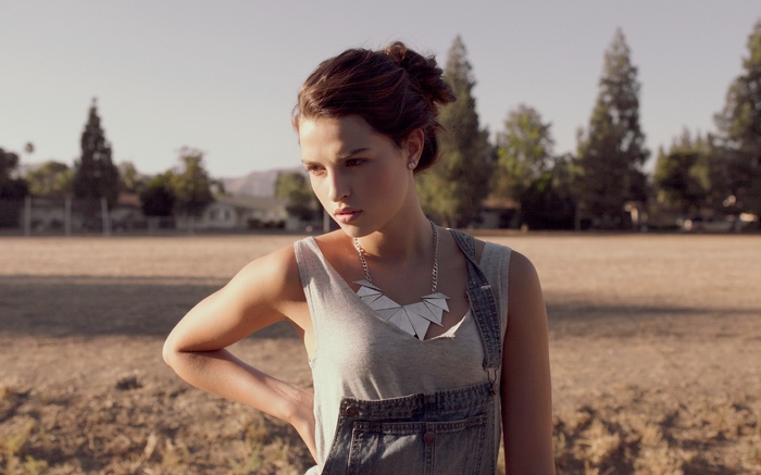 Woman wearing overalls and necklace outdoors