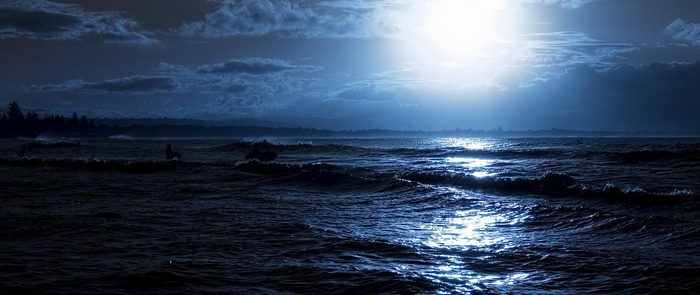 Moonlight over the sea with surfers
