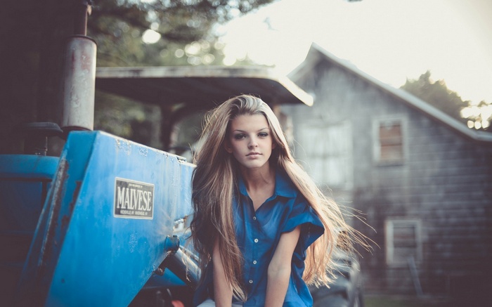 Woman with long blonde hair on a blue tractor