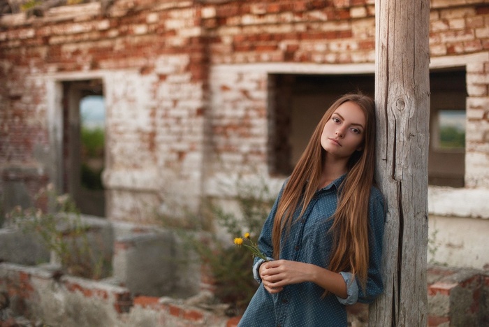 Woman leaning against a wooden post with flowers