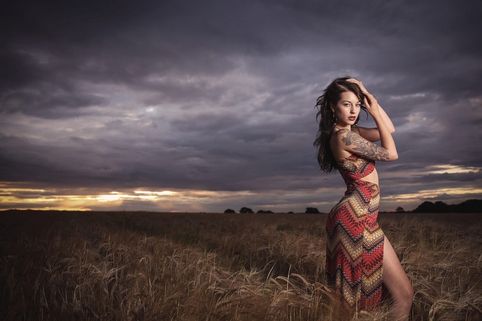 Woman with tattoos in a field at sunset