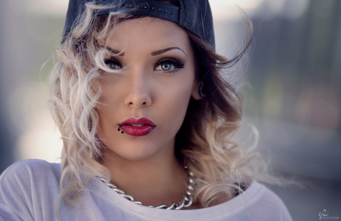 Woman with blonde hair wearing a baseball cap and necklace