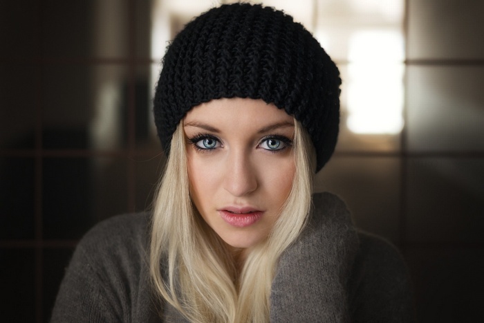 Woman with blonde hair and blue eyes wearing a black beanie