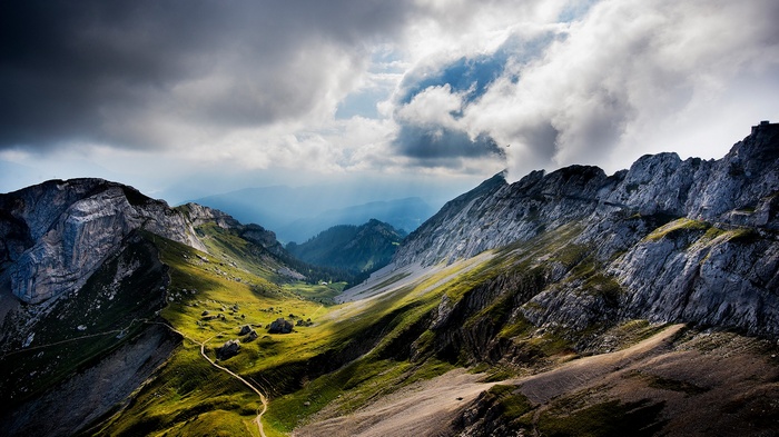 Dramatic mountain landscape with clouds and a winding path