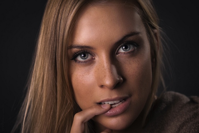 Woman with blonde hair and finger in mouth