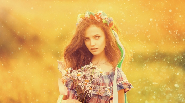 Woman with flower wreath and daisies in sunlight