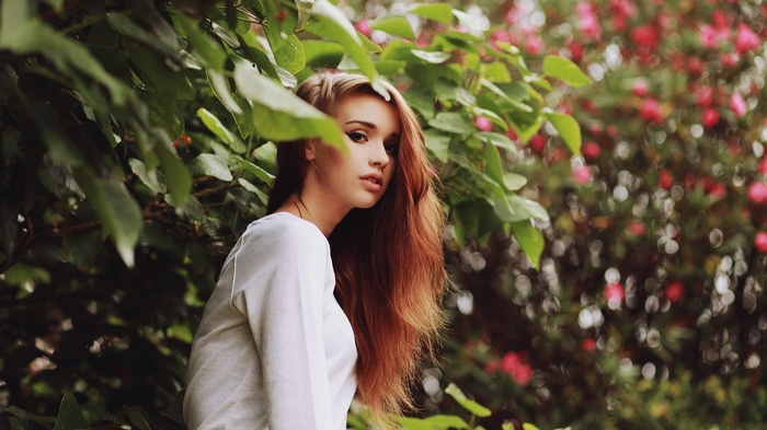 Woman with long auburn hair in white clothing outdoors