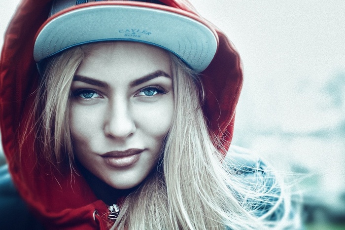 Woman with blonde hair wearing a red hoodie and a cap