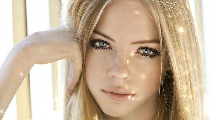 Blonde woman with blue eyes and hand on face