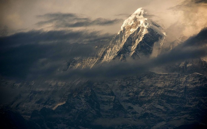 Snowy peak in the Himalayas shrouded in clouds