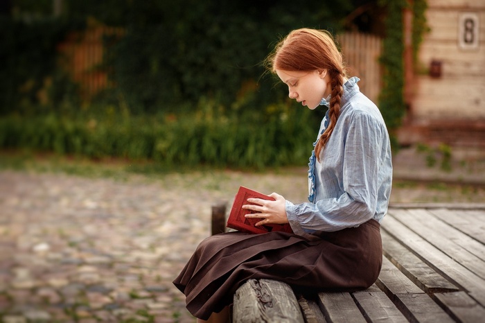 Redhead girl sitting and reading a book