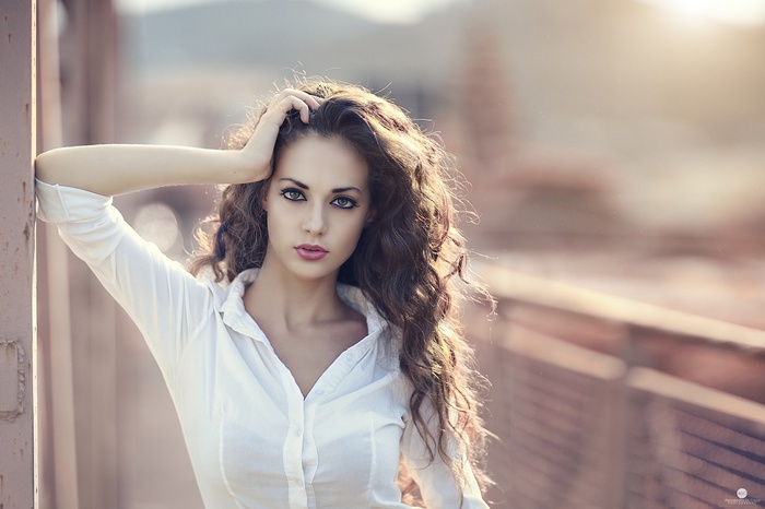 Woman with curly brown hair in a white shirt