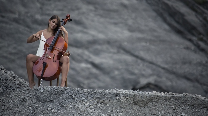 Woman playing cello outdoors on rocky terrain