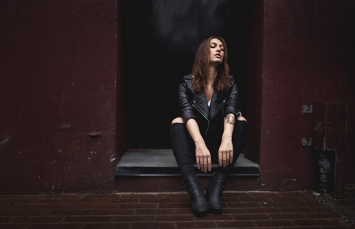 Woman in leather jacket sitting with eyes closed