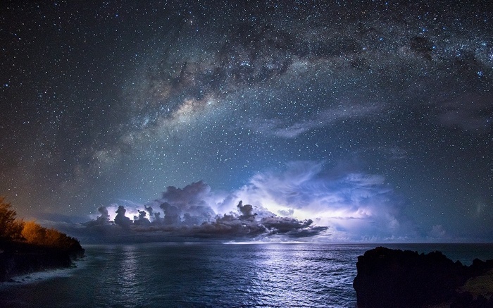 Milky Way over the ocean with lightning