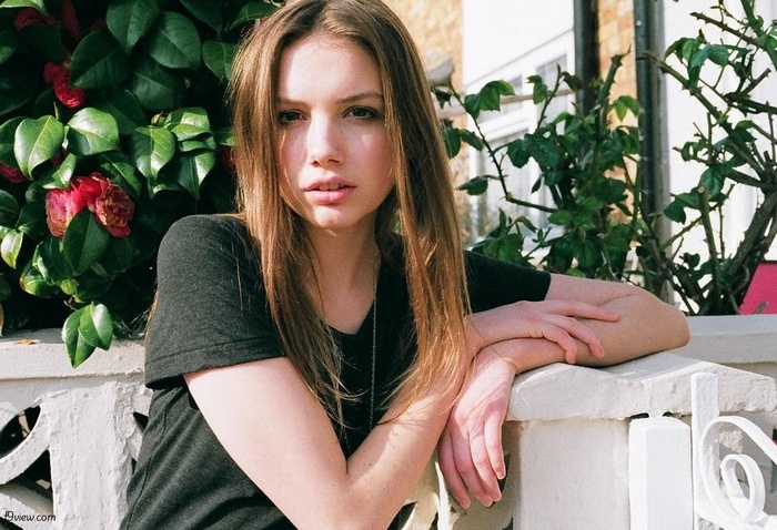 Hannah Murray leaning on a fence