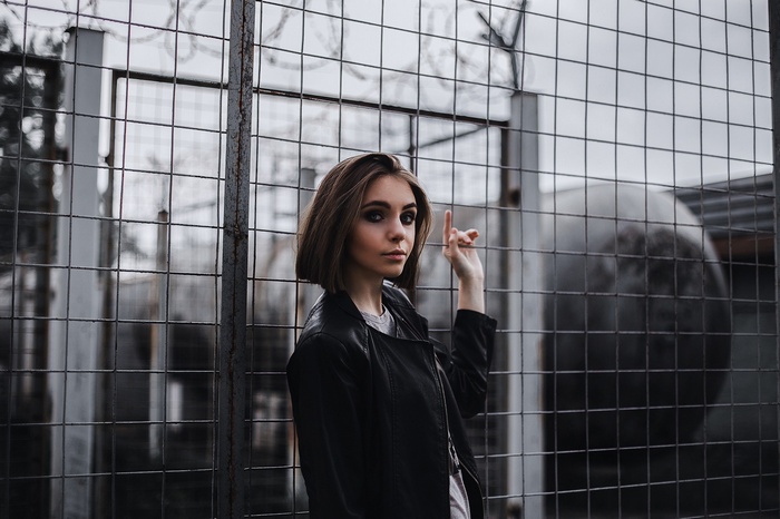 Woman in leather jacket behind a fence
