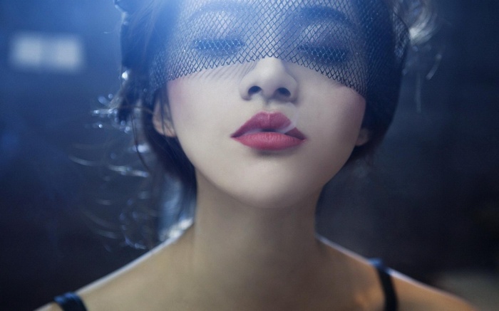 Woman wearing a black veil with smoke