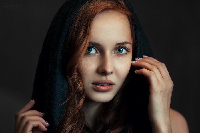 Portrait of a redhead woman wearing a dark hood