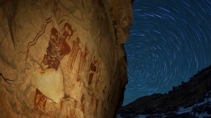 Ancient petroglyphs on a rock face under a starry sky in Utah