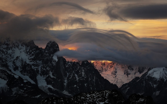 Dramatic clouds over snowy Alps mountains at sunset