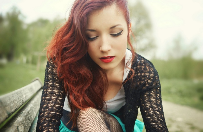 Redhead woman with red lipstick sitting on a bench