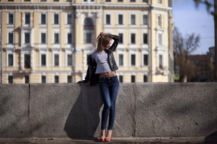 Woman in jeans and high heels leaning on a wall