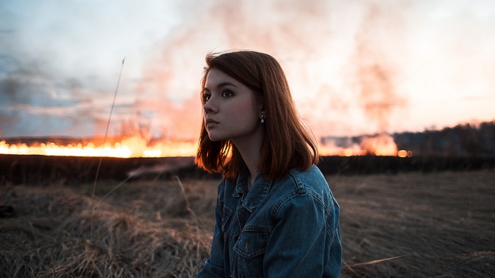 Woman in denim jacket with fire in the background