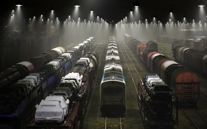 Nighttime rail yard with rows of trains and cars