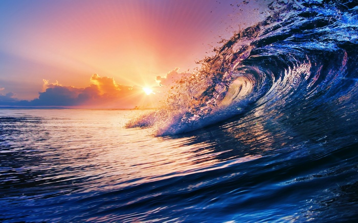 Ocean wave crashing at sunset with colorful sky