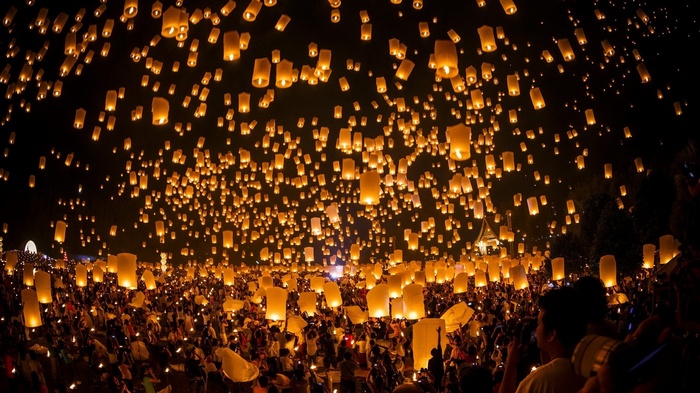 Thousands of lanterns float into the night sky above a crowd